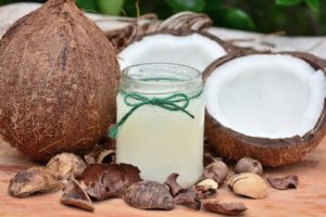 Coconuts next to a jar of coconut oil