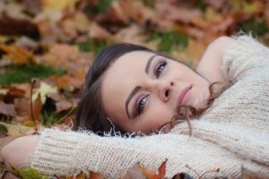 Girl relaxing on the ground in the fall with leaves around her.